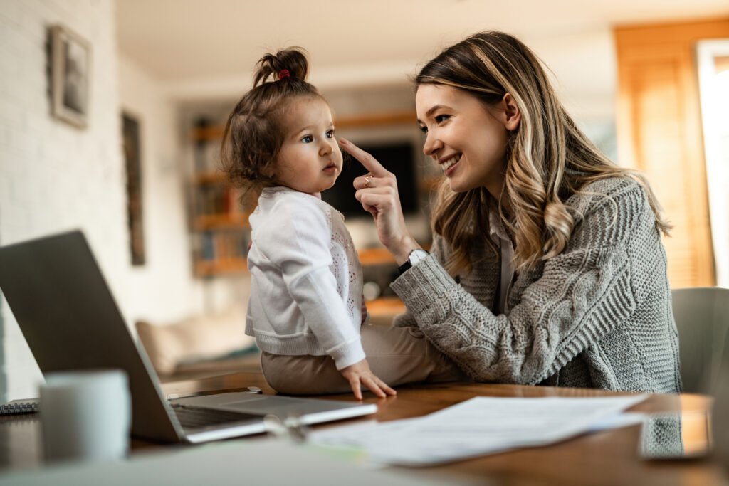 Happy mother having fun while touching daughter nose at home.